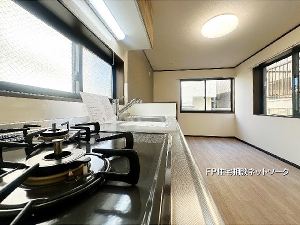 コンロ前の大きな窓で明るさと換気をしっかり確保。料理中も視界が抜け、家族との会話が続くキッチン設計。毎日の調理が心地よい時間に変わります。