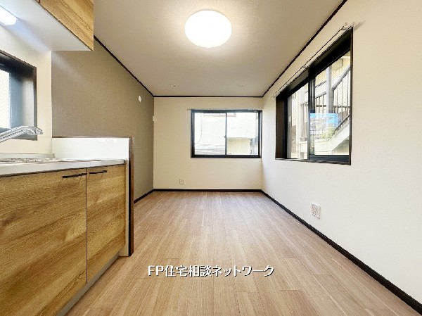 木目調のキッチンがやさしく調和するシンプルな空間。窓から光が入り、ダイニングセットもゆったり配置できる使い勝手の良いレイアウトです。