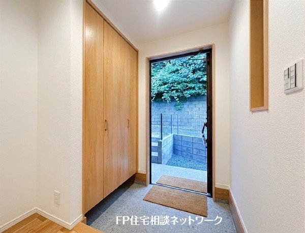 【玄関】  木の温もりが感じられる、明るく開放的な玄関。天井まで続く大容量のシューズクロークで、いつでも整頓された空間に。ガラスドアから見える緑の景色が、心地よい暮らしを演出します。